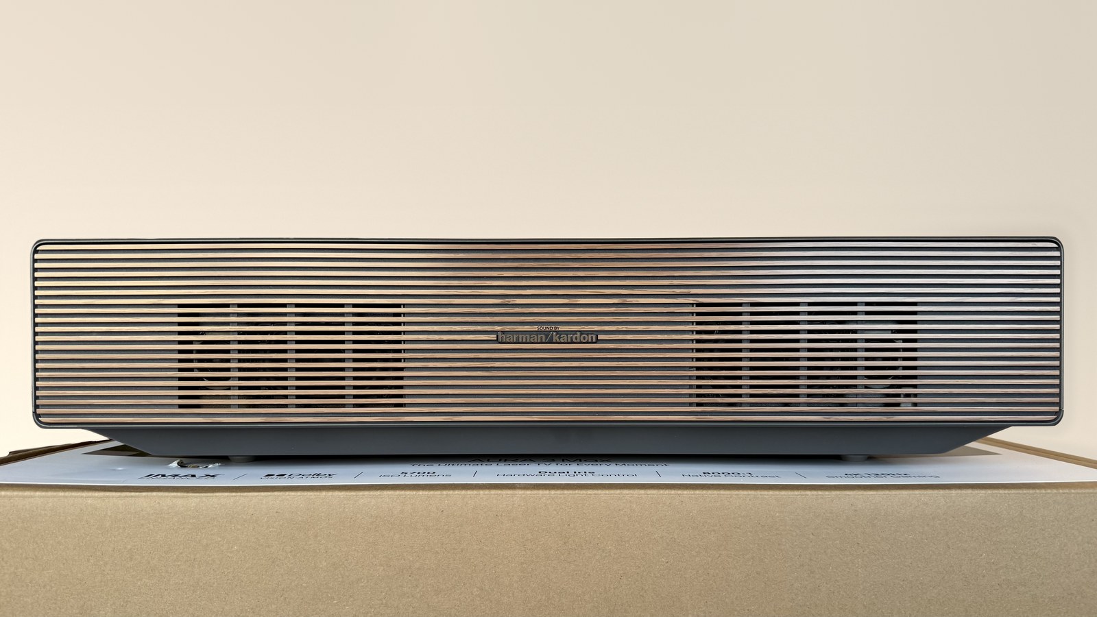 AURA 3 Max спереди: решётка под дерево во всю ширину корпуса, по центру логотип Harman Kardon